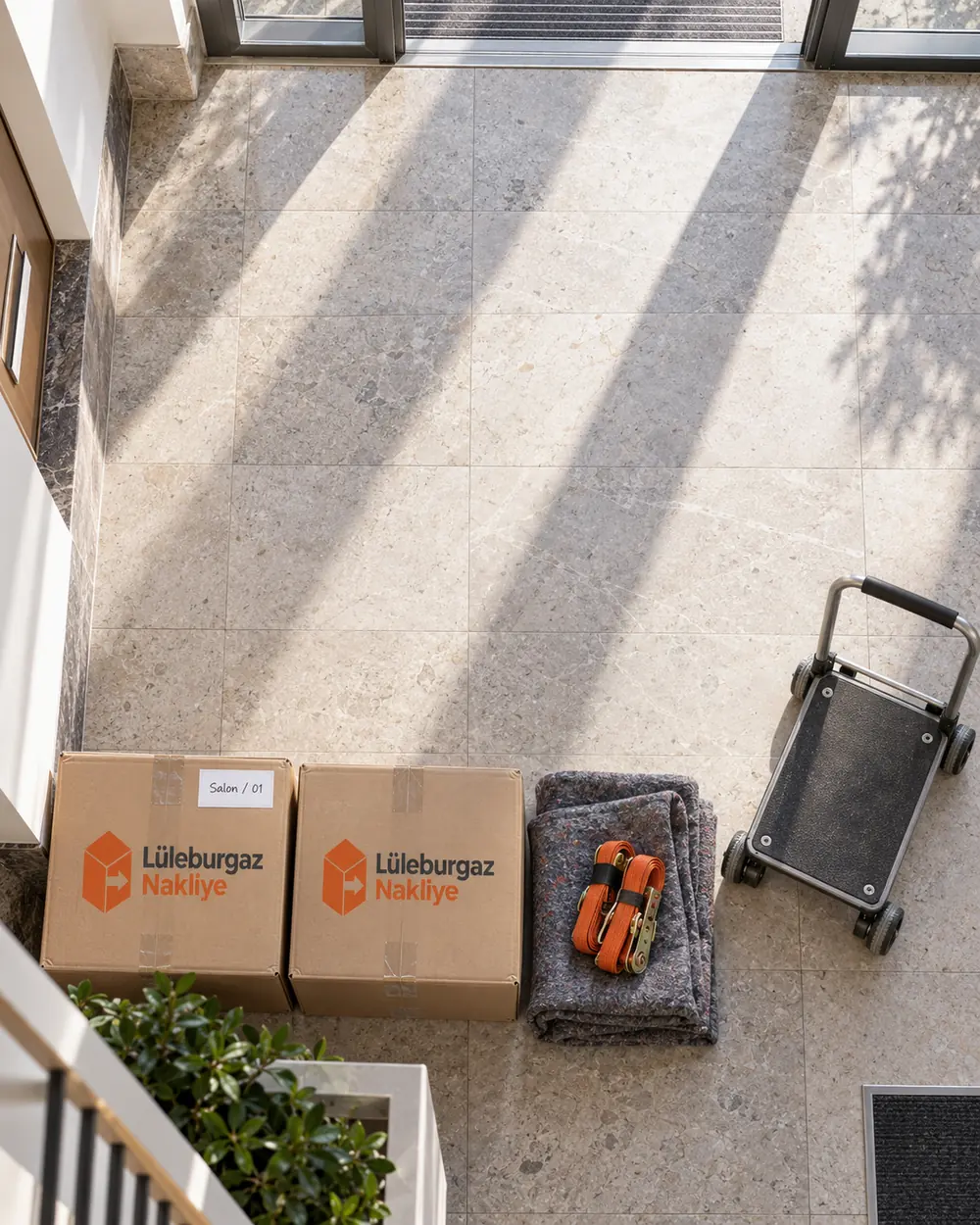 Apartman girişinde etiketli koliler, taşıma arabası ve sabitleme kayışları, üstten görünüm